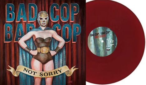 Text: "BAD COP BAD COP" oben, "NOT SORRY" auf einem Banner. Illustration: Frau im Wrestler-Outfit mit Masken. Ganz in Farbe.