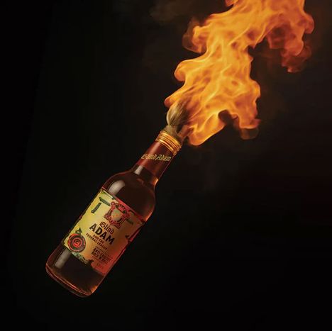 Flasche mit Etikett "Blind Adam", in Flammen; schwarzer Hintergrund.