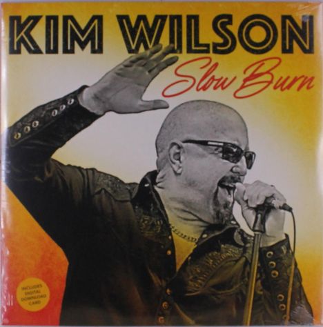 Texte: „KIM WILSON Slow Burn“. Ein Mann mit Sonnenbrille singt leidenschaftlich in ein Mikrofon.