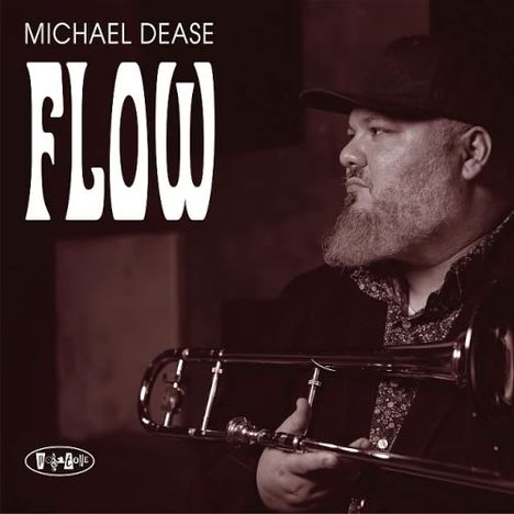 TEXT: "MICHAEL DEASE FLOW". Ein bärtiger Mann mit Mütze hält eine Posaune, Sepia-Ton.