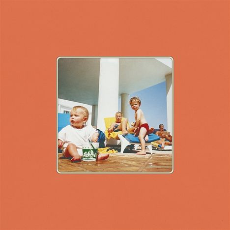Ich kann den Text nicht lesen. Eine retro Fotografie zeigt Kinder und Erwachsene, die sich auf Liegen unter einer Terrasse sonnen.