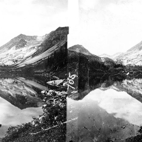 "705" ist auf einer alten Fotografie von Bergen und einem See zu sehen, die sich im Wasser spiegeln.