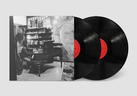 Die Szene zeigt eine Person, die an einem Flügel spielt. Im Hintergrund sind Bücher und kreidebeschriebene Wände.