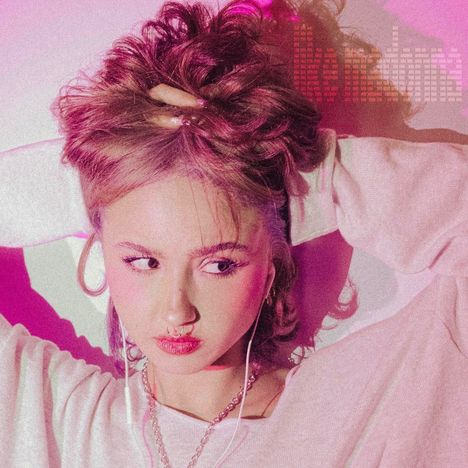 Der Text "like madonna" erscheint. Eine Frau hält ihr Haar, trägt Ohrringe und eine Kette, in pink beleuchtet.