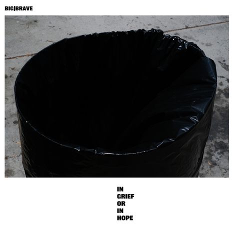 Text: "IN GRIEF OR IN HOPE". Oben links steht "BIG|BRAVE". Ein großer schwarzer Plastiksack steht auf einem grauen Boden.