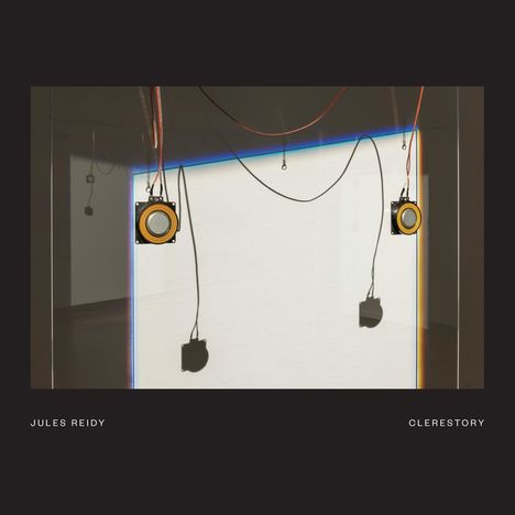 Text: "Jules Reidy Clerestory". Schatten von Lautsprechern mit Kabeln auf einer weißen Wand.
