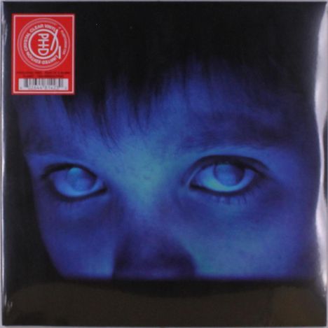 Rotes Etikett links oben mit weißem Logo. Dominante blaue Beleuchtung zeigt ein nahes Gesicht mit intensiven Augen.