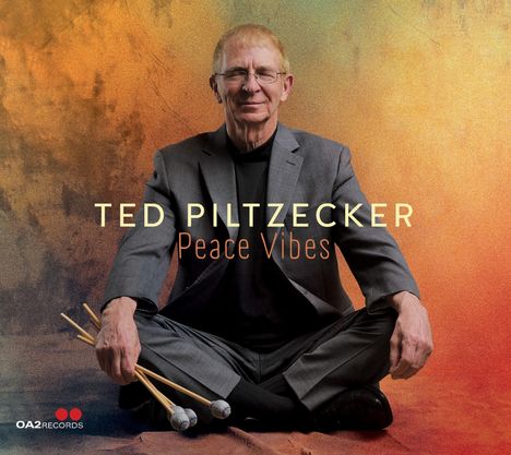"Ted Piltzecker, Peace Vibes." Ein älterer Mann in Anzug sitzt mit geschlossenen Augen im Schneidersitz, hält Schlegel.