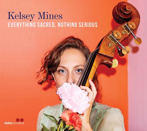 "Kelsey Mines, Everything Sacred, Nothing Serious." Frau mit Blumen und Kontrabass vor orange-pinkem Hintergrund.