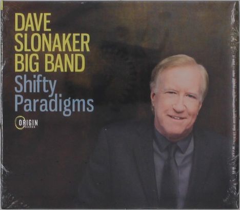 Cover mit den Worten: "DAVE SLONAKER BIG BAND Shifty Paradigms". Ein lächelnder Mann in Anzug und Krawatte. Logo von Origin Records.