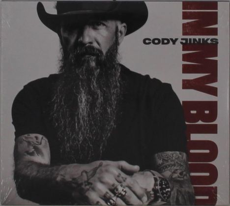 Der Text lautet "CODY JINKS" und "IN MY BLOOD". Ein Mann mit Vollbart und Hut, tätowierte Arme, ernstes Gesicht.