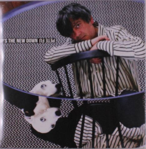 Text: "P3cE (TI) UP'S THE NEW DOWN".  
Ein Mann in gestreiftem Hemd lehnt auf einem Stuhl, ein Hund darunter schaut hoch.