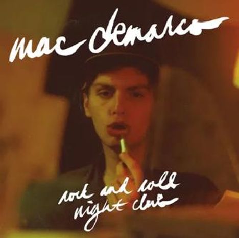 "Mac Demarco rock and roll night club." Ein Mann hält einen Lippenstift vor einem Spiegel im Halbdunkel.