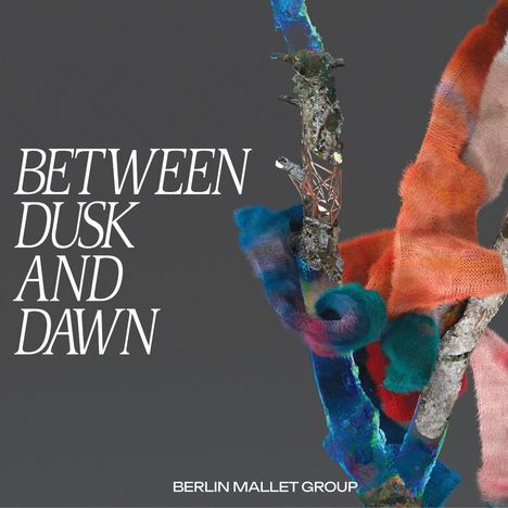 Text: "BETWEEN DUSK AND DAWN" und "BERLIN MALLET GROUP". Illustration: Ein Ast mit bunten, flauschigen Stoffen umwickelt.