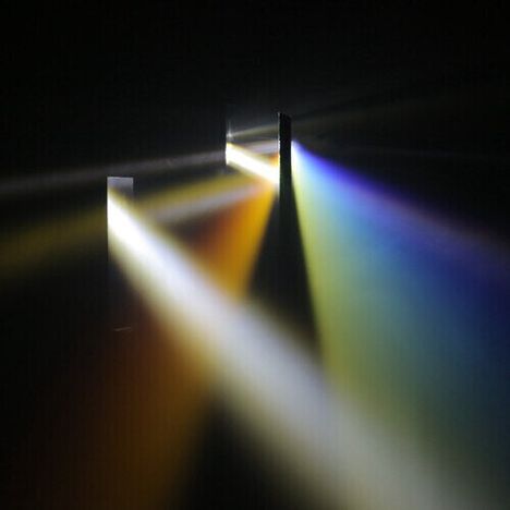 Mehrfarbige Lichtstrahlen strahlen durch dunkle Öffnungen und erzeugen ein faszinierendes Lichtschauspiel.