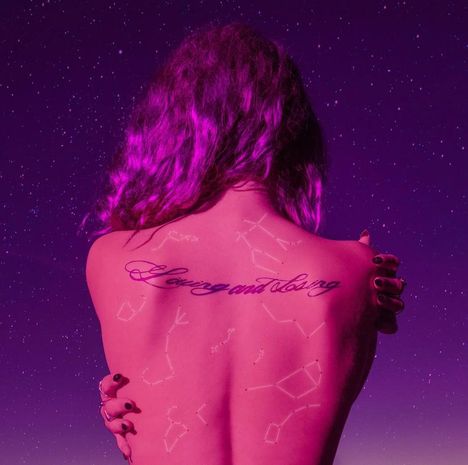 Der Text "Loving and Losing" ist auf einem Rücken tätowiert. Der Hintergrund ist ein lilafarbener Sternenhimmel.