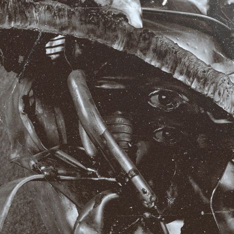 Zerquetschtes Metall, darunter zwei gemalte Augen, alles in sepia gehalten, wirkt rostig und abgenutzt.
