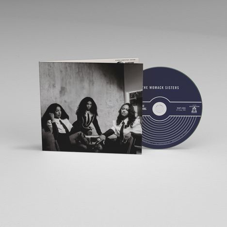 Text auf CD: "THE WOMACK SISTERS". Schwarze CD neben einem schwarz-weißen Foto von drei elegant gekleideten Frauen.