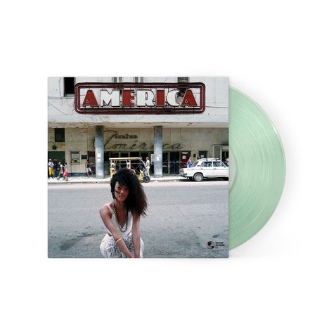 Text: "AMERICA" auf einem großen Schild. Eine Frau hockt auf der Straße, im Hintergrund ein altes Auto und Gebäude. Vinyl-Schallplatte.