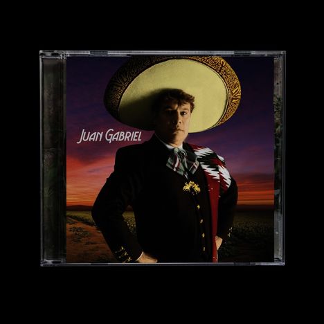 "Juan Gabriel" steht in weißer Schrift. Ein Mann in traditioneller Kleidung mit Sombrero vor einem Sonnenuntergang.