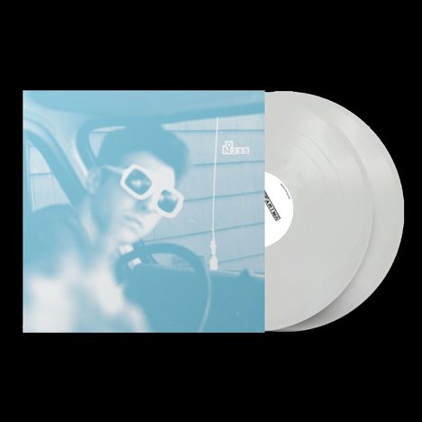 Ein verschwommenes Cover mit "N° 235"; eine Person trägt große Sonnenbrillen. Daneben zwei weiße Schallplatten.