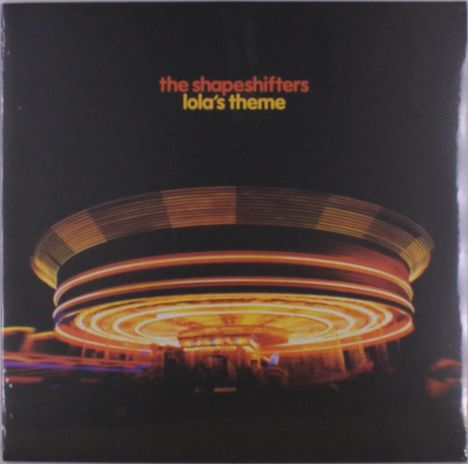 Text: "the shapeshifters - lola's theme". Bunte Lichter eines Karussells drehen sich schnell im Dunkeln.