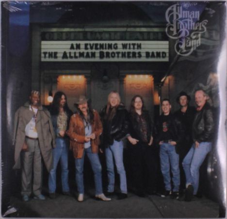 "An Evening with The Allman Brothers Band" auf einem Theaterbanner. Neun lächelnde Personen posieren entspannt davor.