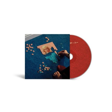 „In the Room“ auf einer roten CD. Hände setzen ein blaues und rosa Puzzle mit einem Porträt auf einem Teppich zusammen.