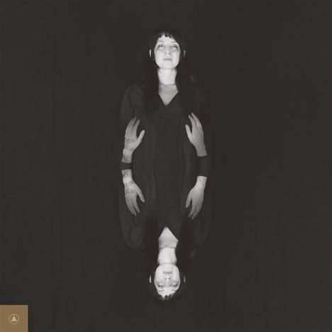 Ein schwarz-weißes Foto zeigt eine Person in der Mitte mit gespiegeltem Abbild darunter, auf schwarzem Hintergrund.