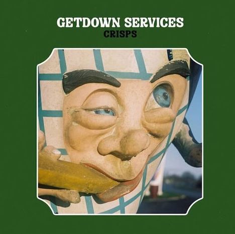 „GETDOWN SERVICES CRISPS“. Eine Statue eines Gesichtes mit schräg lächelndem Ausdruck, das an einem Strohhalm saugt.