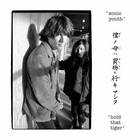 Texte: „sonic youth“, japanische Schriftzeichen, „hold that tiger“. Ein Mann und eine Frau in einem Gang mit Schatten.