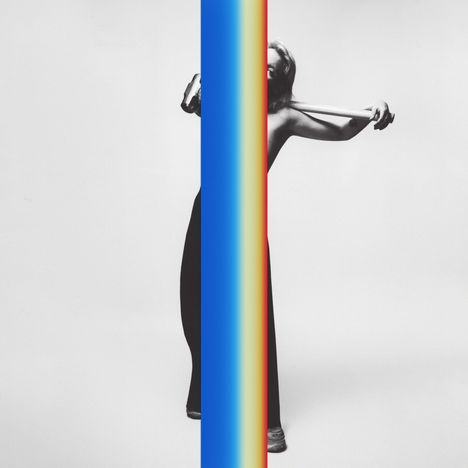 Eine Person hinter einem bunten, vertikalen Streifen, der in Blau, Rot und Gelb verläuft. 