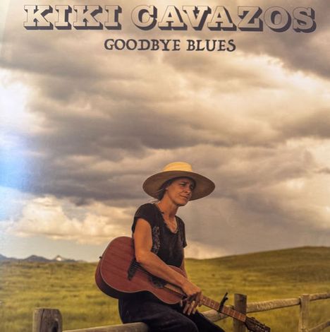 "KIKI CAVAZOS", "GOODBYE BLUES". Frau mit Gitarre und Hut sitzt auf einem Holzzaun vor bewölktem Himmel und Wiese.