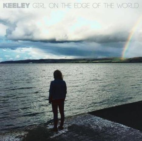 Text: "KEELEY GIRL ON THE EDGE OF THE WORLD." Eine Person steht am Ufer, blickt aufs Meer. Ein Regenbogen ist sichtbar.