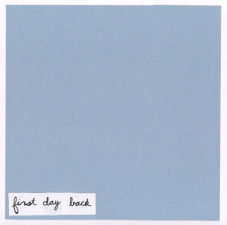 Text: "first day back". Einfache Illustration mit hellblauem Hintergrund und Text in schwarzer Handschrift unten links.