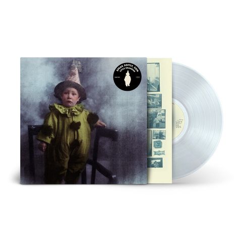 Text "SPEAK SOFTLY SON" auf einem schwarzen Aufkleber. Kind in einem grünen Kostüm mit spitzem Hut in rauchiger Umgebung. Transparente Vinyl-Schallplatte daneben.