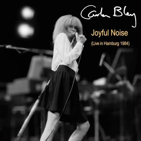 Carla Bley, "Joyful Noise (Live in Hamburg 1984)". Frau singend auf Bühne in Schwarz-Weiß.