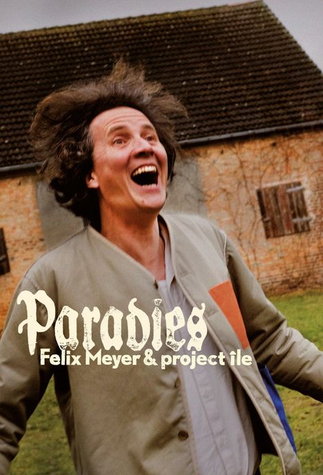 „Paradies Felix Meyer & project île“. Ein Mensch mit freudigem Ausdruck im Vordergrund, ein Haus im Hintergrund.