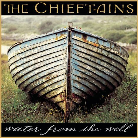 Texte: "The Chieftains", "water from the well". Altes Boot auf Gras, naturbelassene Umgebung.