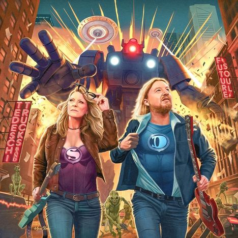 Futuristische Stadt mit riesigem Roboter, zwei Superhelden mit Gitarren. Schilder: "TEDESCHI TRUCKS BAND" und "FUTURE".