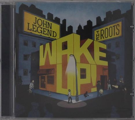 "JOHN LEGEND" und "THE ROOTS" oben, "WAKE UP!" in großer Schrift. Illustration: Stadtlandschaft mit beleuchteter Straße.