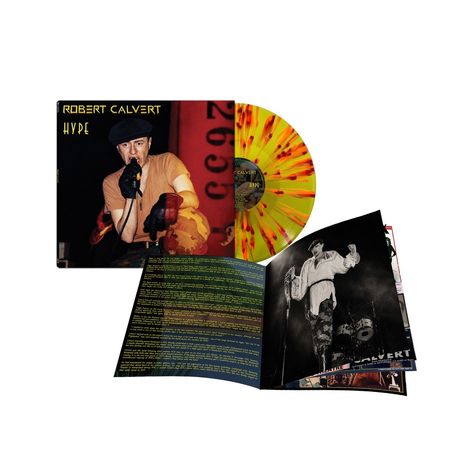 „Robert Calvert Hype“ steht links oben. Eine gelb-orange Vinyl-Schallplatte, daneben ein aufgeschlagenes Booklet.