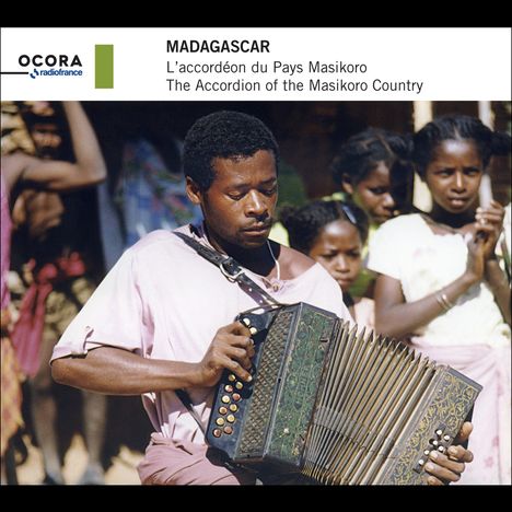 "Madagascar: L'accordéon du Pays Masikoro. Ein Mann spielt Akkordeon, umgeben von Zuschauern in traditioneller Kleidung."