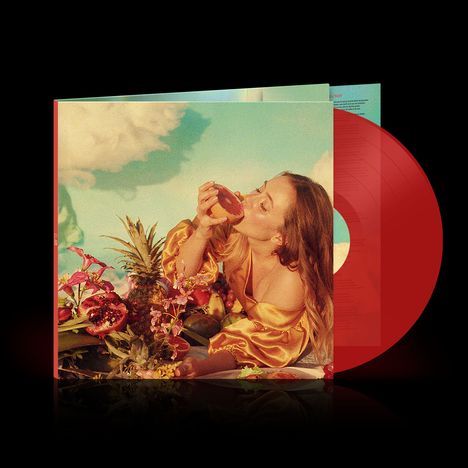 Albumcover: Eine Person in gelbem Kleid isst Obst, umgeben von Blumen und Früchten, vor einem blauen Himmel. Rote Schallplatte.