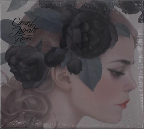 "Cœur de pirate Roses" ist in eleganter Schrift. Darstellung eines Frauengesichts im Profil mit dunklen Blüten im Haar.
