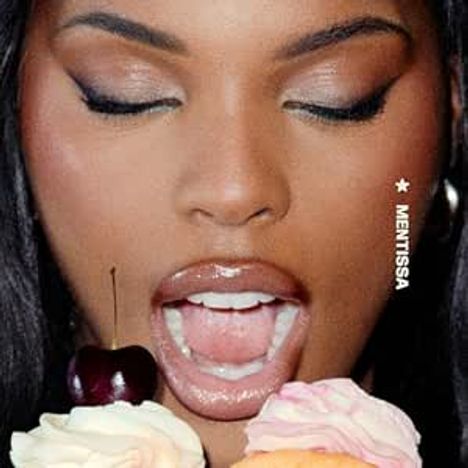MENTISSA, Frau mit geschlossenen Augen öffnet Mund vor zwei Cupcakes, einer mit Kirsche. Lippen glänzend.