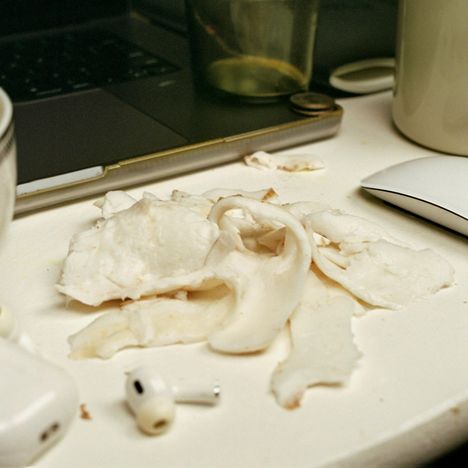 Weißes Gemüse, Laptop-Tastatur, leeres Glas, weiße Tasse, weiße Computermaus, ein AirPod auf einem Tisch.