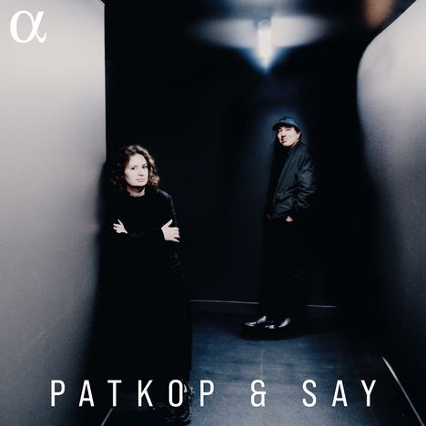 Text: "PATKOP & SAY". Zwei Personen stehen in einem dunklen Flur. Eine Person lehnt an der Wand, die andere steht im Hintergrund.