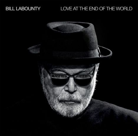 „BILL LABOUNTY“, „LOVE AT THE END OF THE WORLD“. Ein Mann mit Hut und Sonnenbrille, reflektiert Klaviertasten.