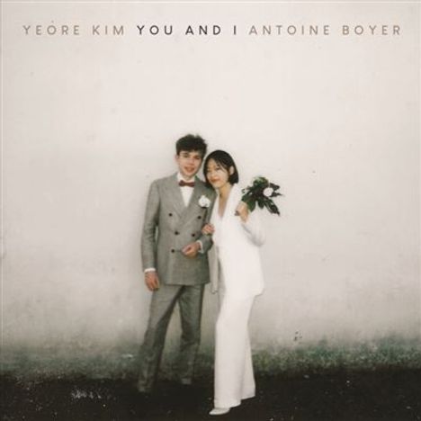 Text: "YEORÉ KIM YOU AND I ANTOINE BOYER". Ein Paar in eleganter Kleidung vor einer neutralen Wand, sie hält Blumen.